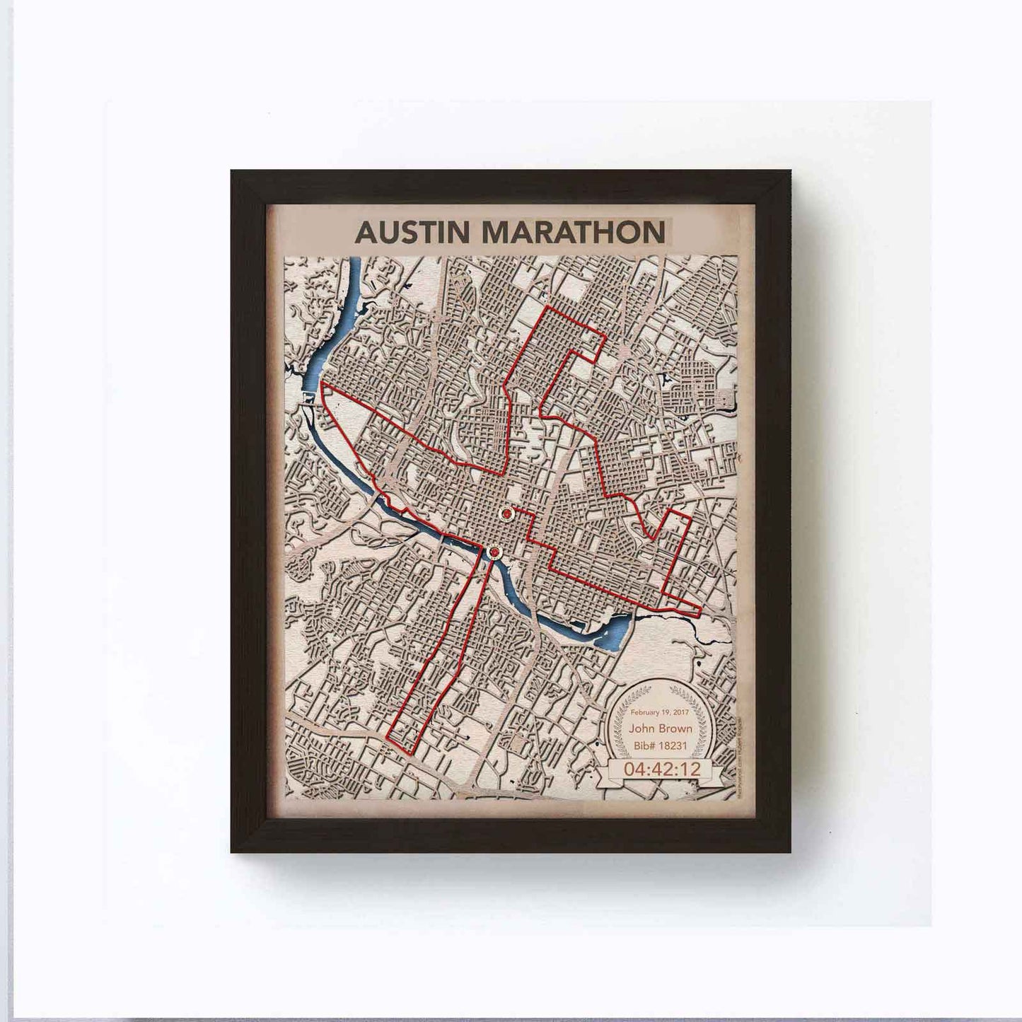 Framed artwork depicting a red route map over Austin, Texas, labeled "Austin Marathon." Includes a date, name, bib number, and time at the bottom.