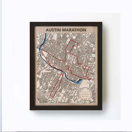 Framed artwork depicting a red route map over Austin, Texas, labeled "Austin Marathon." Includes a date, name, bib number, and time at the bottom.